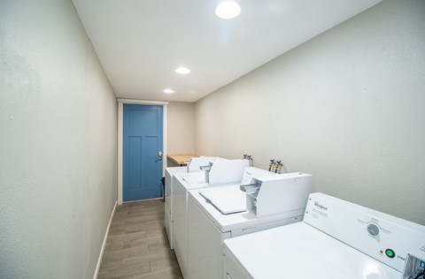 A small, white, modern kitchen with a blue door.